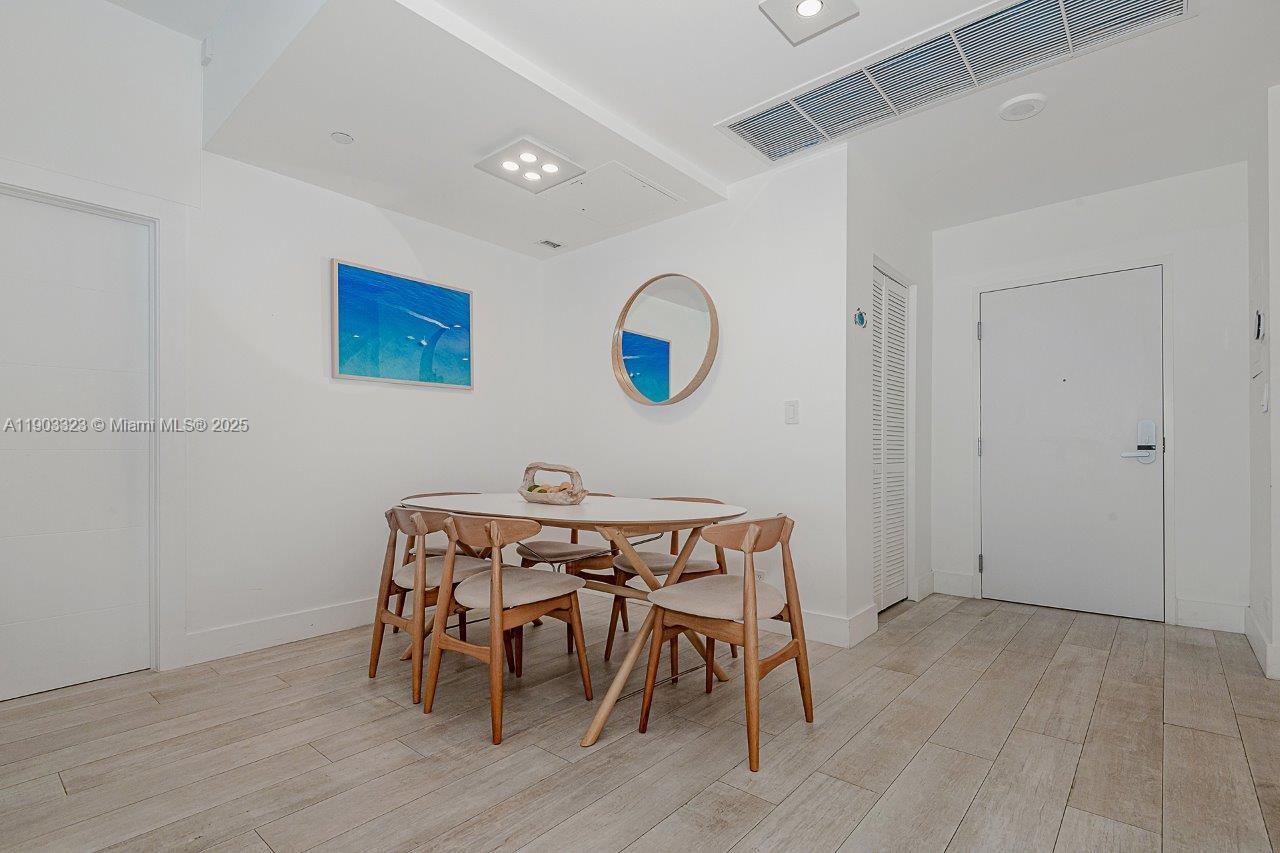 A dining area features a wooden table with four chairs, a round mirror, and artwork — 2301 Collins Ave, Miami Beach FL 33139, MIAMI BEACH, FL