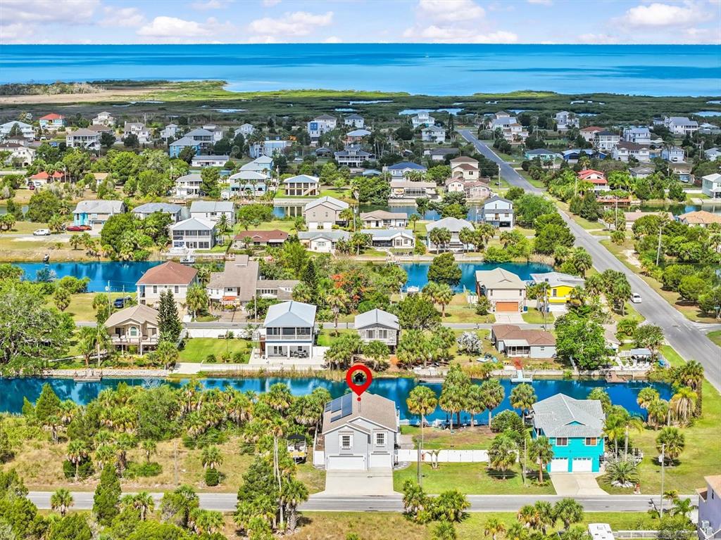 An aerial view shows a residential neighborhood with houses situated along a canal near water — 3305 ROSE ARBOR DRIVE, HERNANDO BEACH, FL