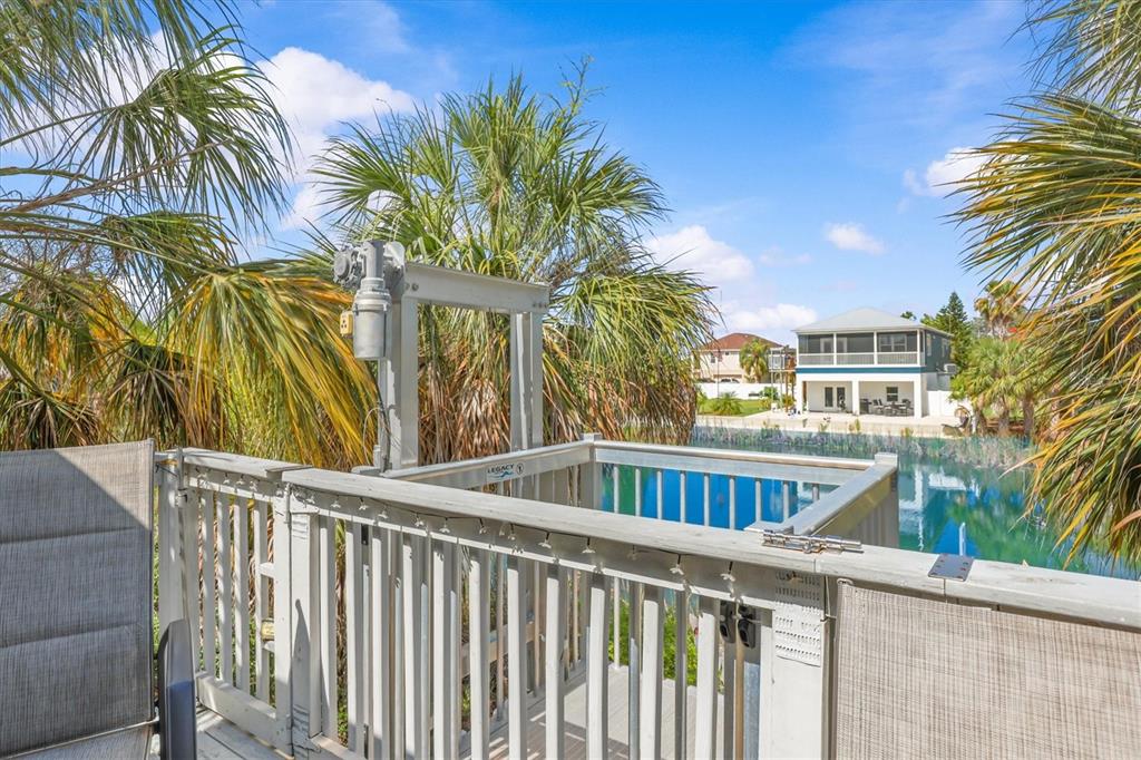 An outdoor deck features a white wooden railing and a mechanical lift overlooking a canal — 3305 ROSE ARBOR DRIVE, HERNANDO BEACH, FL