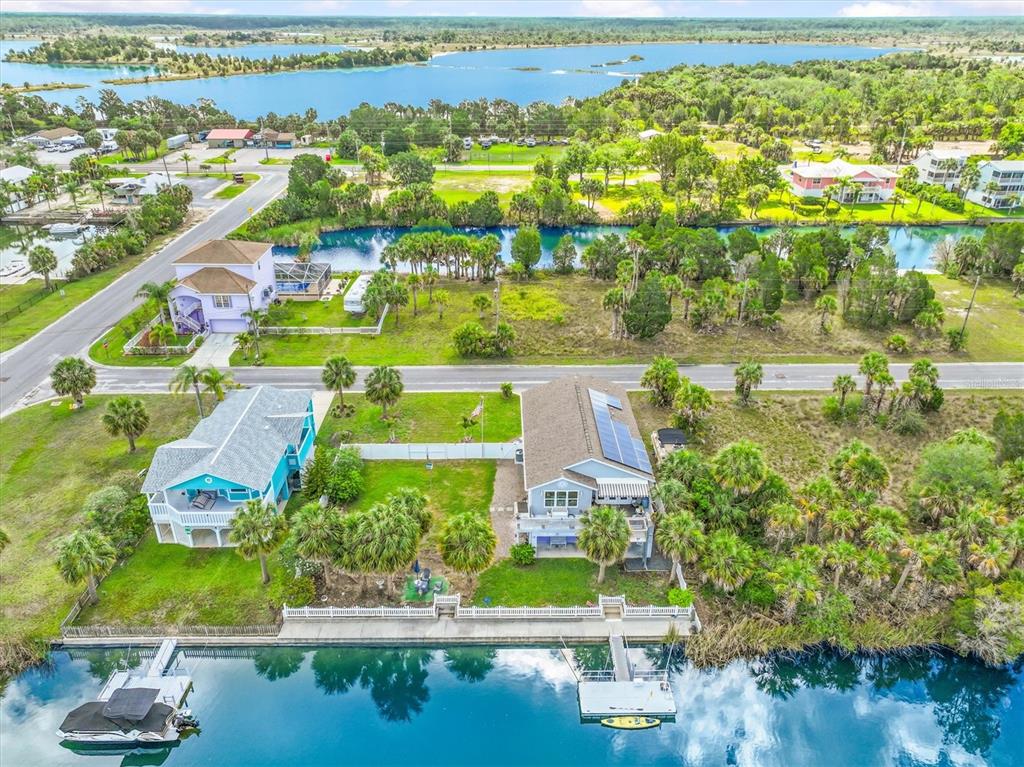 An aerial view shows two waterfront houses with private docks along a canal near a lake — 3305 ROSE ARBOR DRIVE, HERNANDO BEACH, FL