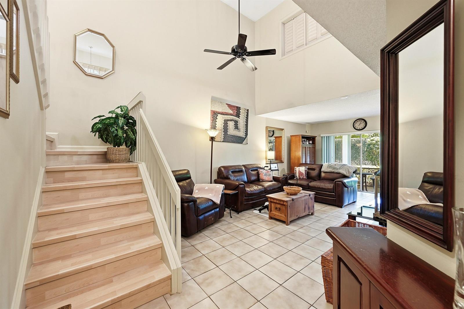 A living room with tile floors, leather furniture, and a staircase leading to a loft — 2118 Discovery Circle W, Deerfield Beach FL 33442, DEERFIELD BEACH, FL