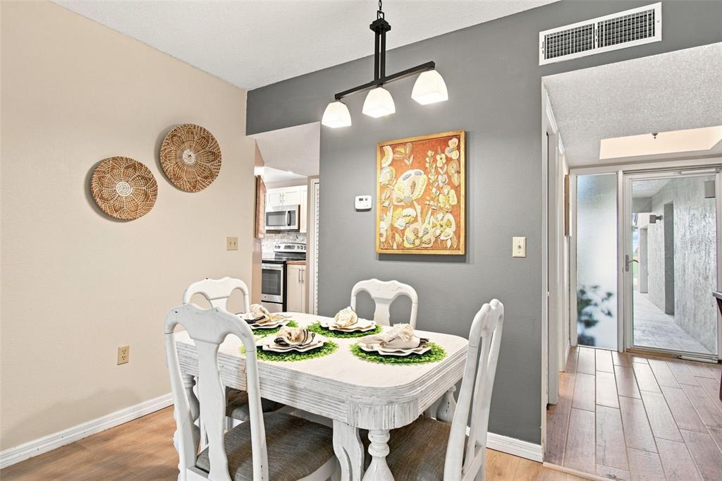 A dining area features a white table, four chairs, and a modern light fixture — 4701 DUHME ROAD UNIT 1D, MADEIRA BEACH, FL