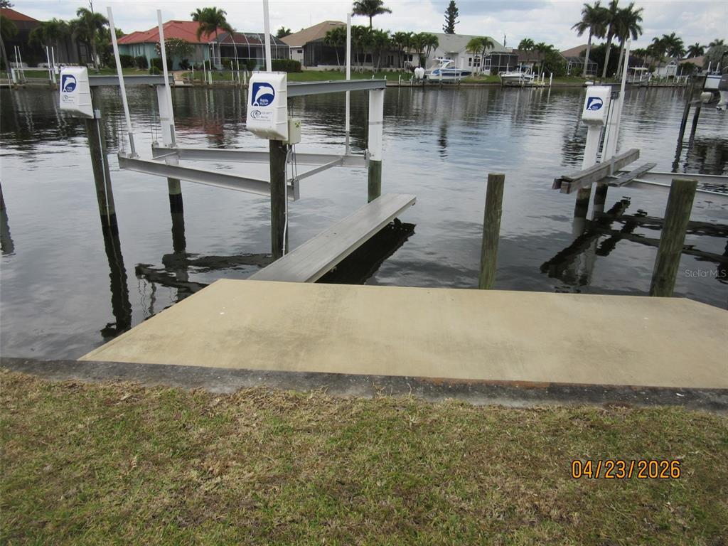 A concrete dock leads to a boat lift situated in a canal behind a house — 562 MONACO DRIVE, PUNTA GORDA, FL
