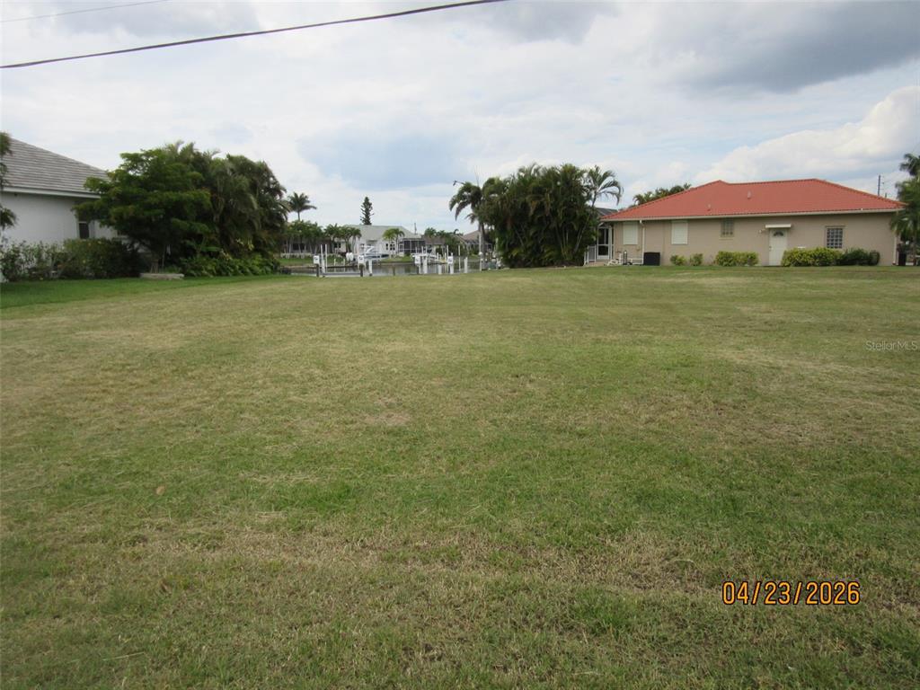 A grassy vacant lot sits between two houses with a view of a canal — 562 MONACO DRIVE, PUNTA GORDA, FL
