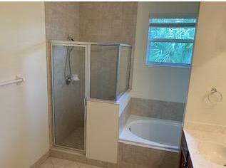 A bathroom features a tiled walk-in shower with a glass door next to a soaking tub — 173 SW Otter Run Place, Stuart FL 34997, STUART, FL