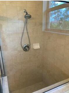 A walk-in shower features beige tile walls, a handheld showerhead, and a small window — 173 SW Otter Run Place, Stuart FL 34997, STUART, FL