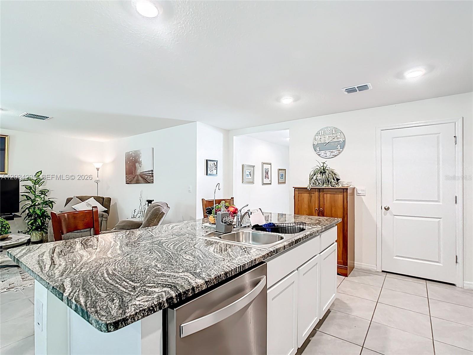 A kitchen island with a granite countertop and stainless steel sink sits in a room — 7161 SW 135TH PLACE, Ocala FL 34473, OCALA, FL