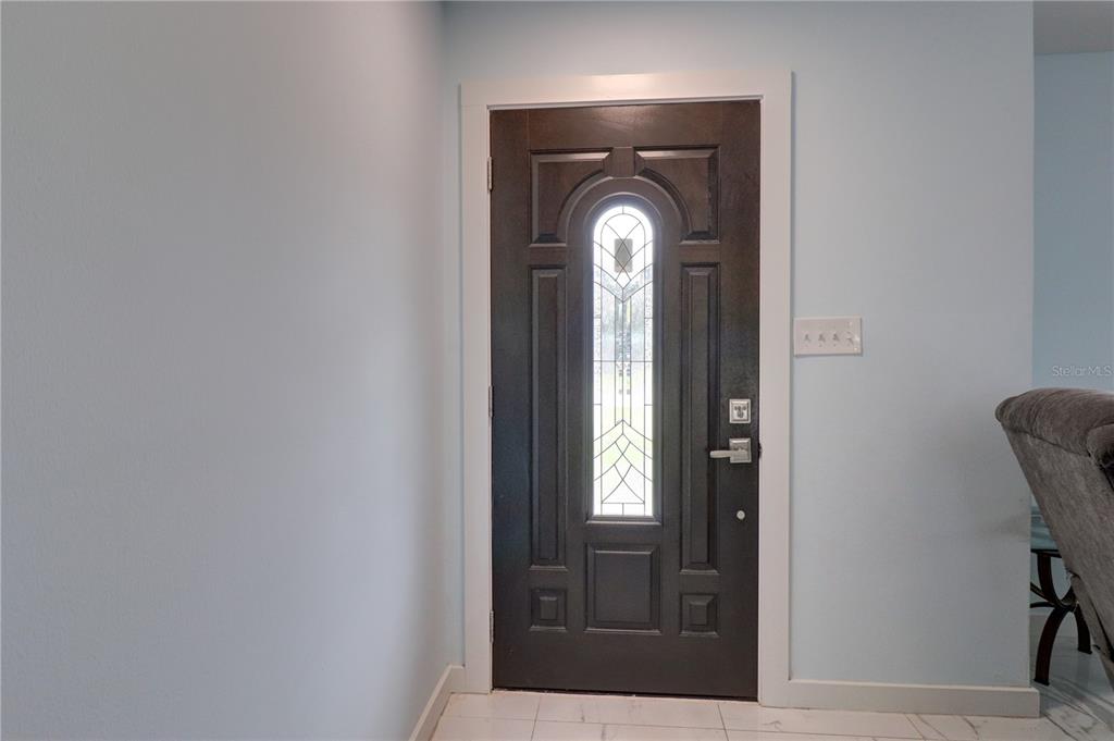 A dark brown front door with a decorative glass insert sits in a light blue entryway — 215 TARPON WAY, PUNTA GORDA, FL