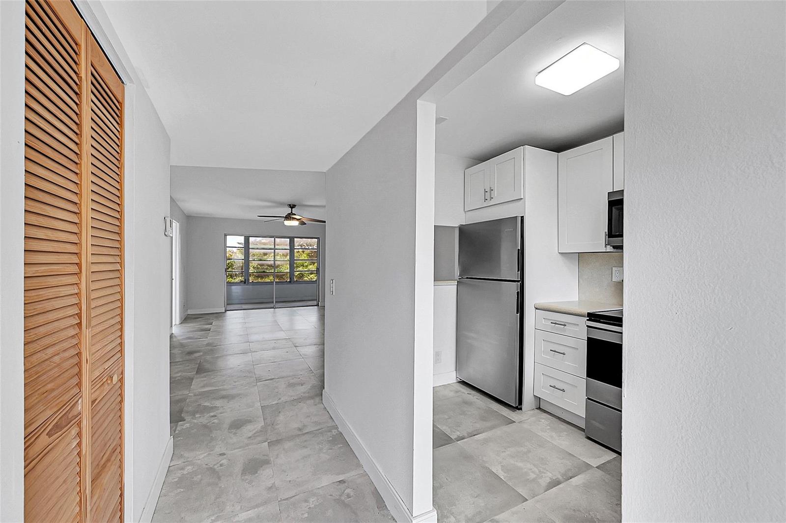 A view from a hallway into a kitchen with stainless steel appliances and a living area — 9761 Sunrise Lakes Boulevard # 301, Sunrise FL 33322, SUNRISE, FL