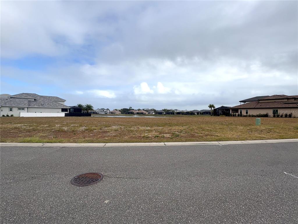 A vacant residential lot sits in front of a pond and several houses — 48 DEL PALMA DRIVE, PALM COAST, FL