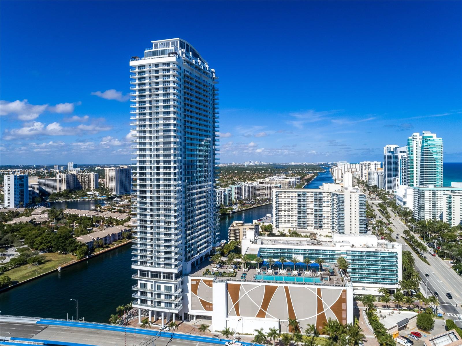 An aerial view shows a tall residential skyscraper next to a hotel and canal — 4010 S Ocean Dr # R908, Hollywood FL 33019, HOLLYWOOD, FL