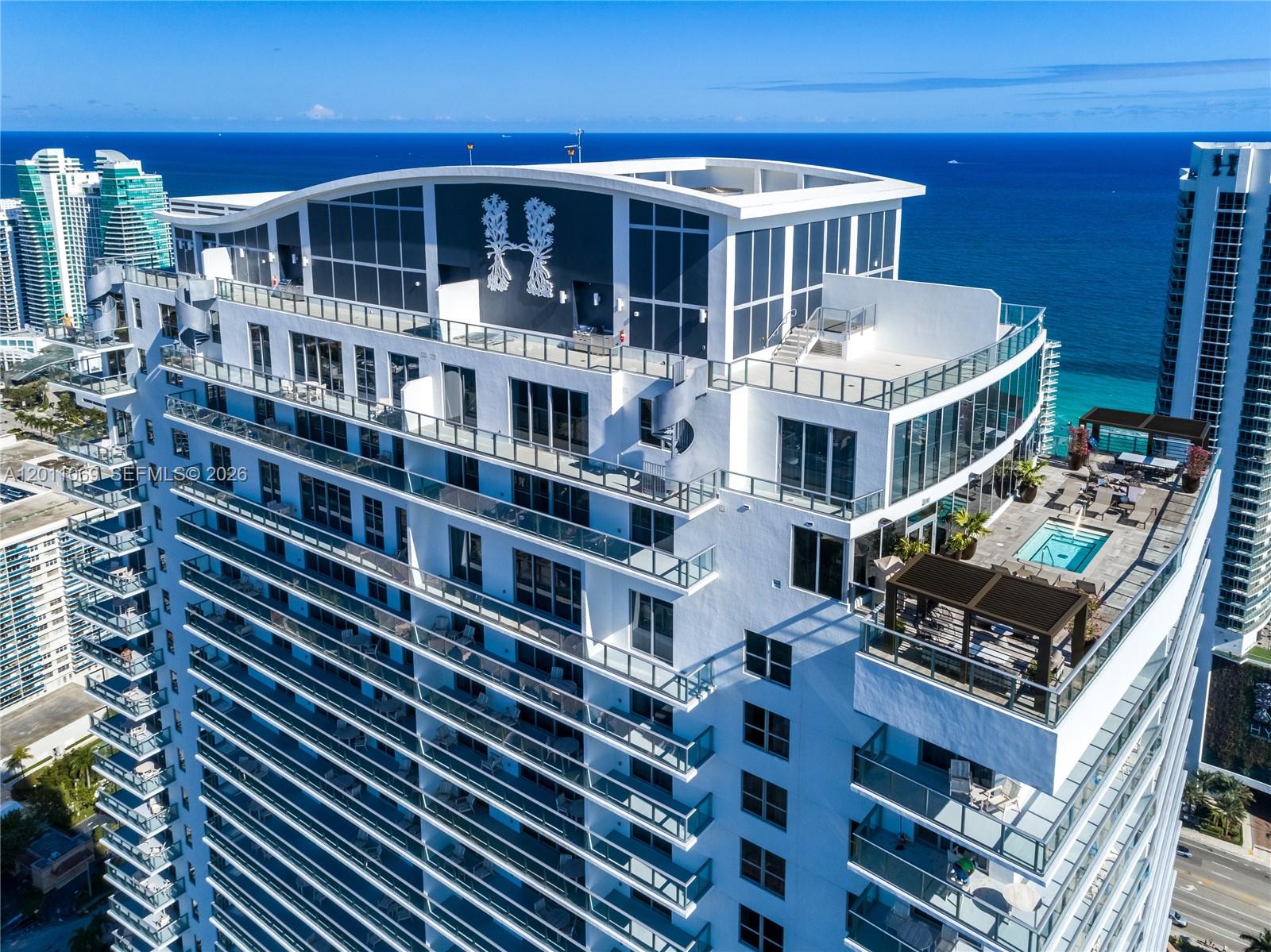 An aerial view shows the exterior of a high-rise building with a rooftop pool deck — 4010 S Ocean Dr # R908, Hollywood FL 33019, HOLLYWOOD, FL