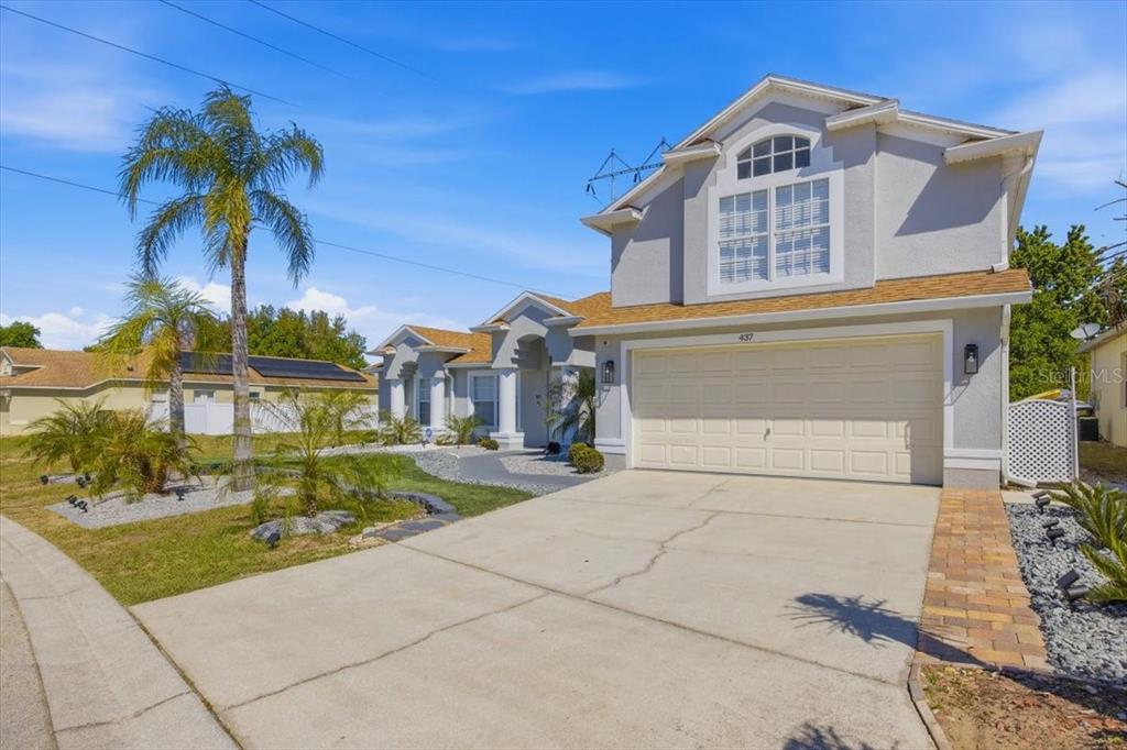 A two-story house with a beige garage, light gray siding, and a palm tree out front — 437 GRAND RESERVE DRIVE, DAVENPORT, FL