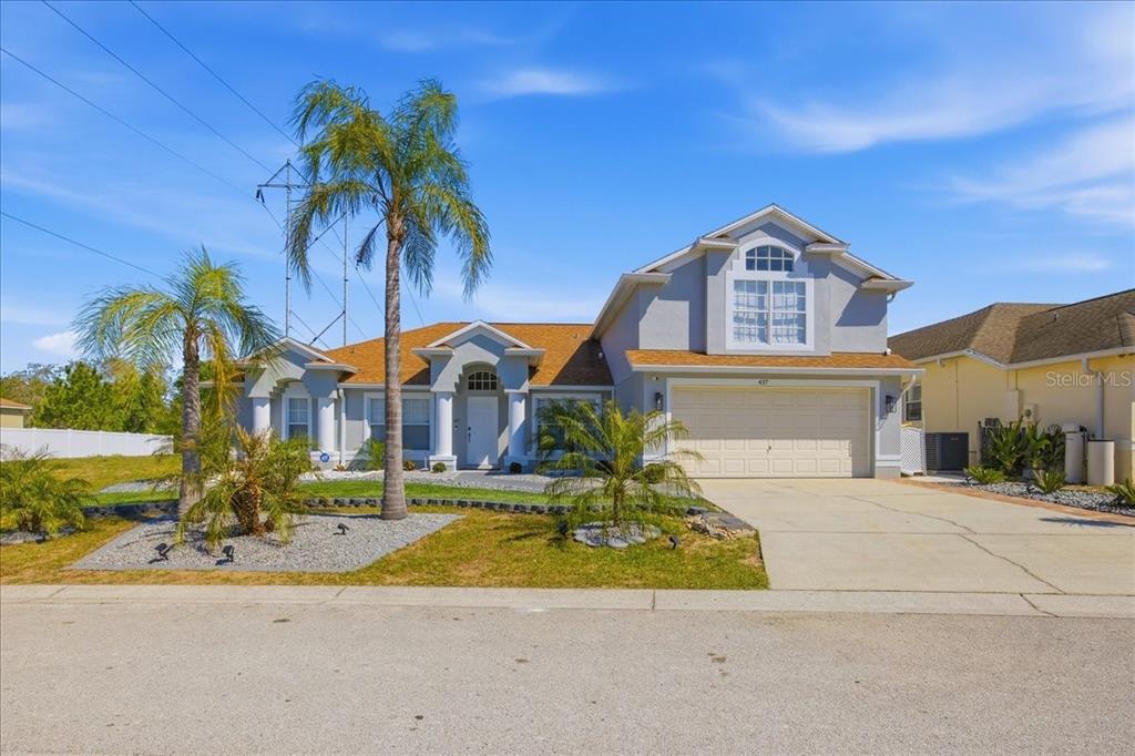 A two-story suburban house with a tan roof, gray stucco exterior, and a two-car garage — 437 GRAND RESERVE DRIVE, DAVENPORT, FL