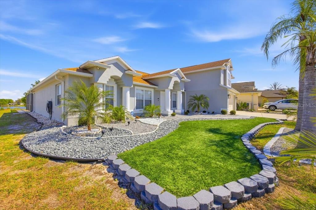 A single-story house with a gray exterior, a stone-bordered lawn, and a gravel garden bed — 437 GRAND RESERVE DRIVE, DAVENPORT, FL