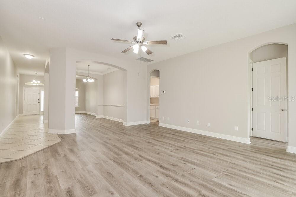 An open living area features light-colored wood-look flooring, a ceiling fan, and arched doorways — 1174 GREEN VISTA CIRCLE, APOPKA, FL