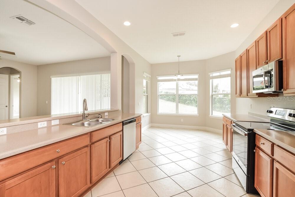 A kitchen with light-colored countertops, wooden cabinets, stainless steel appliances, and tile flooring — 1174 GREEN VISTA CIRCLE, APOPKA, FL