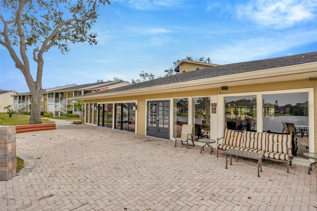 A paved patio area sits outside a building with large windows and a double door — 308 LAKE PARSONS GREEN UNIT 102, BRANDON, FL
