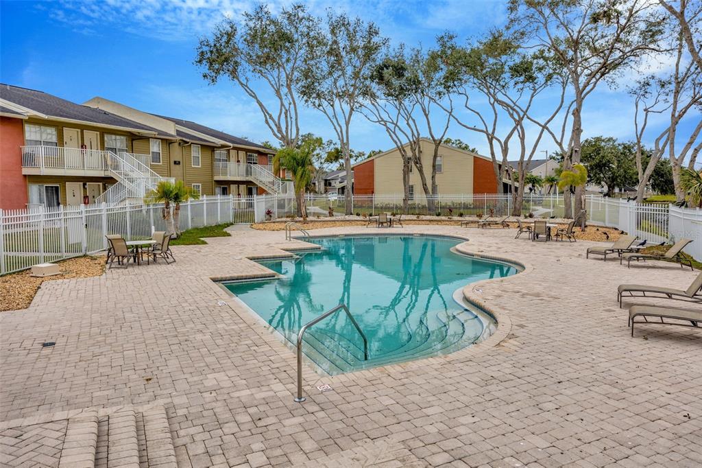 An outdoor swimming pool with a paved deck surrounded by apartment buildings and trees — 308 LAKE PARSONS GREEN UNIT 102, BRANDON, FL