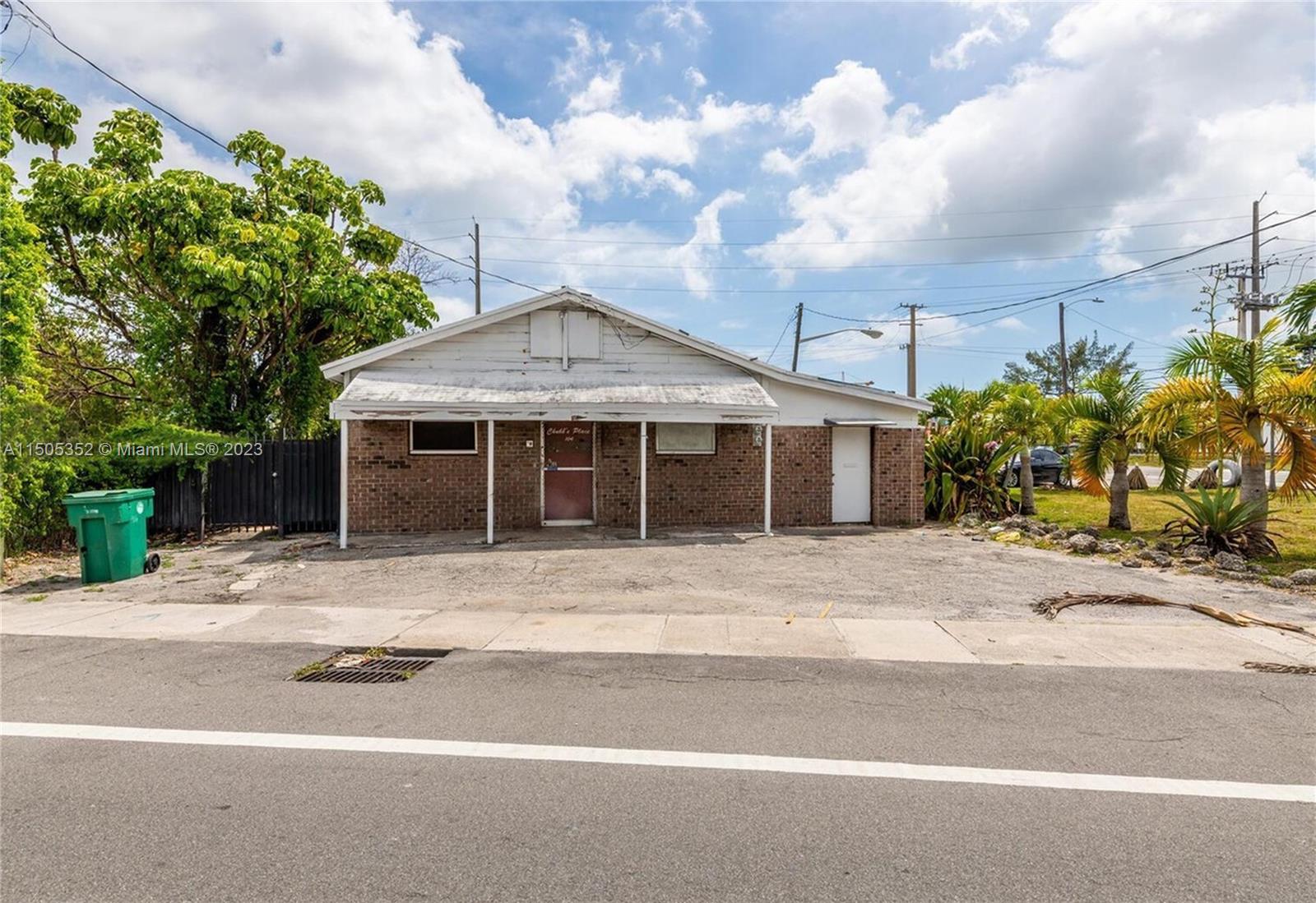 A single-story brick building with a covered porch sits behind a paved parking area — 400 1st St, Dania Beach FL 33004, DANIA BEACH, FL