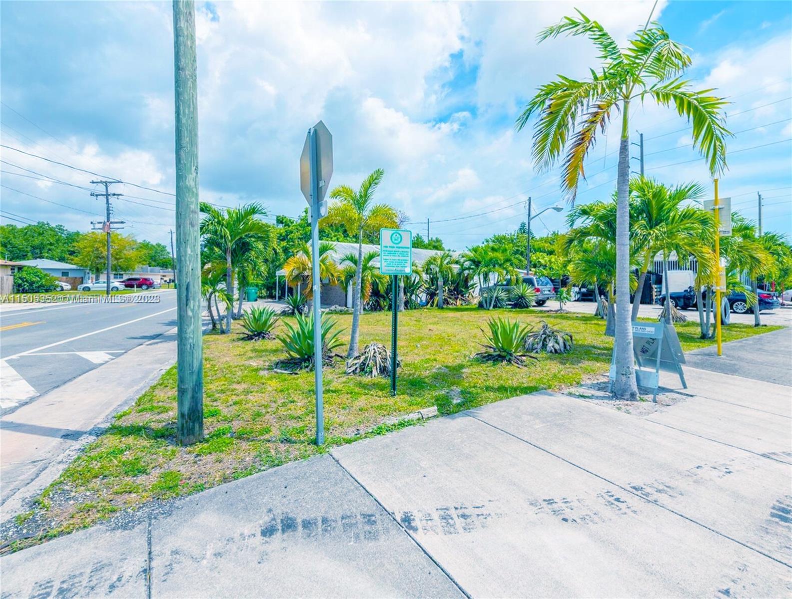 A grassy lot with palm trees, a utility pole, and a street sign — 400 1st St, Dania Beach FL 33004, DANIA BEACH, FL