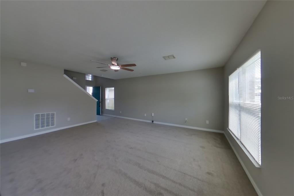 An empty living room features beige carpet, light gray walls, and a ceiling fan — 1708 PORTCASTLE CIRCLE, WINTER GARDEN, FL