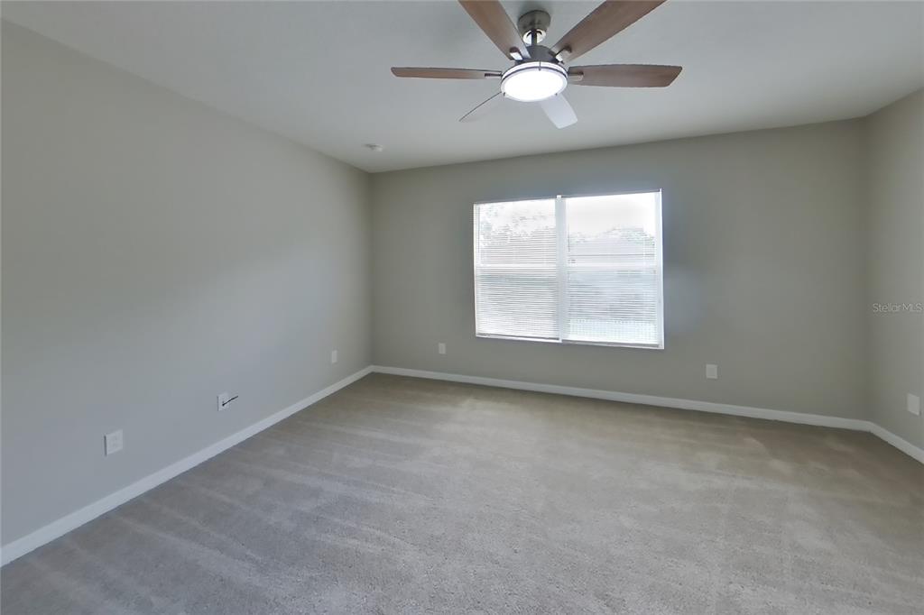 An empty bedroom features light gray walls, beige carpeting, and a ceiling fan — 1708 PORTCASTLE CIRCLE, WINTER GARDEN, FL