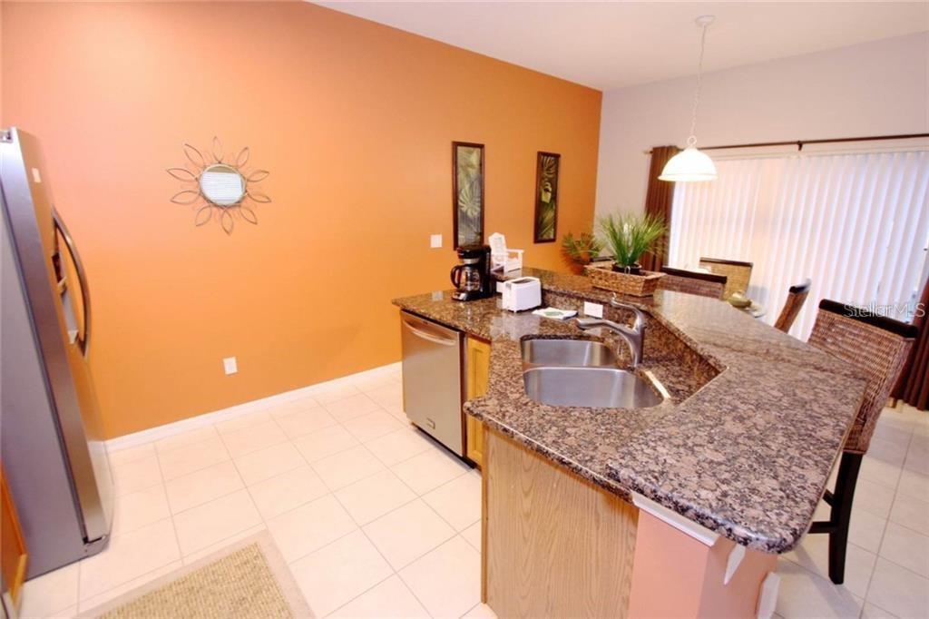 A kitchen features granite countertops, stainless steel appliances, and an orange accent wall — 3152 YELLOW LANTANA LANE, KISSIMMEE, FL