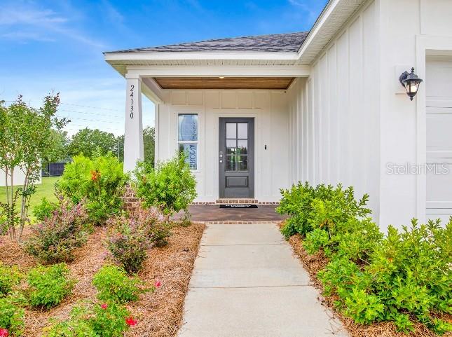 A white house exterior features a covered entryway with a dark door and landscaping — TBD SW 37TH TERRACE, OCALA, FL