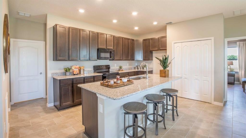 A kitchen features dark wood cabinets, granite countertops, a central island, and tile flooring — TBD SW 37TH TERRACE, OCALA, FL