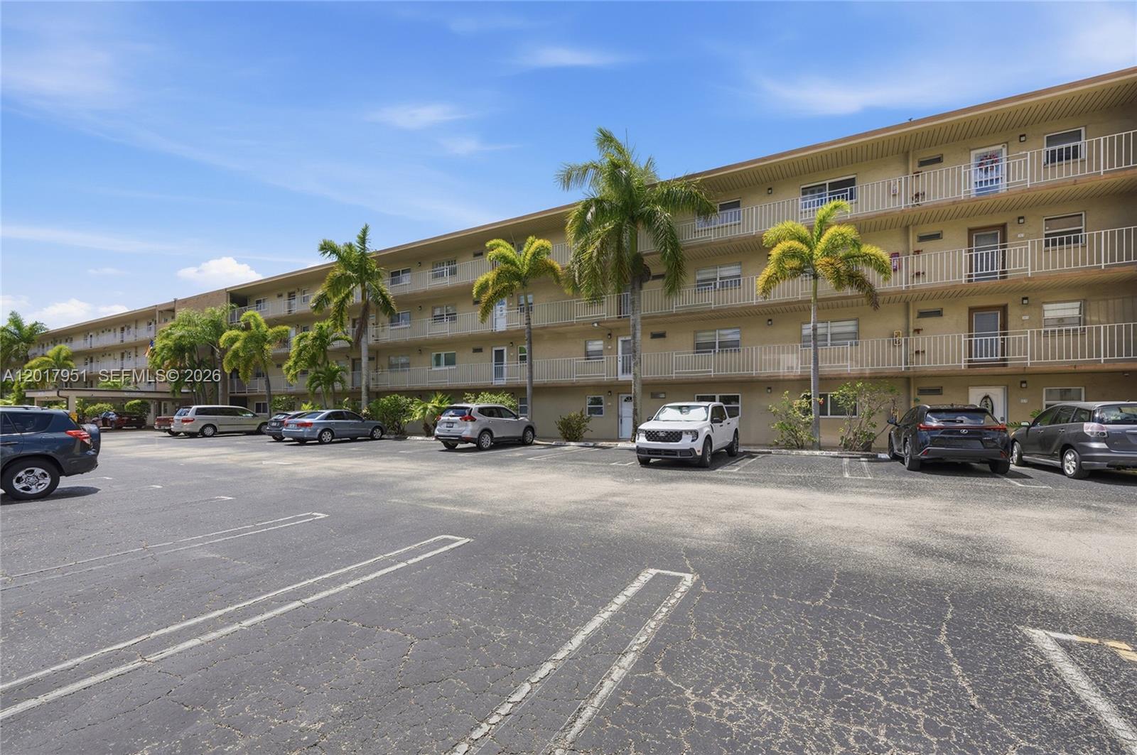 A multi-story apartment building features exterior balconies and a paved parking lot in front — 330 NE 26th Ave # 1120, Boynton Beach FL 33435, BOYNTON BEACH, FL