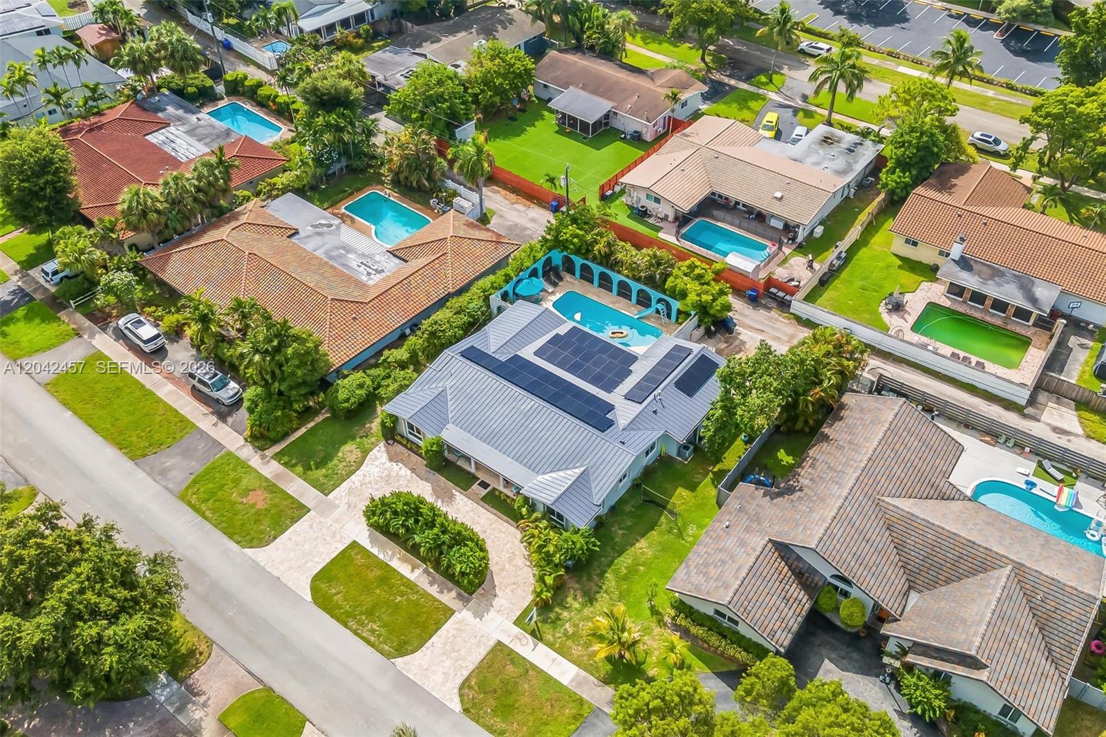 An aerial view shows a suburban neighborhood featuring several houses with swimming pools and solar panels — 633 N Crescent Dr, Hollywood FL 33021, HOLLYWOOD, FL