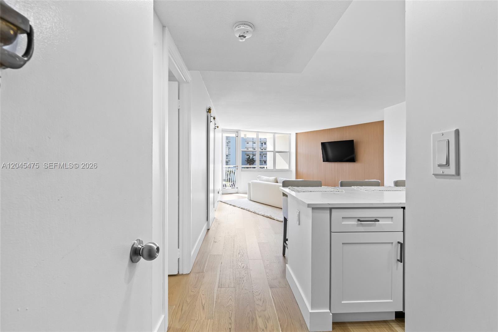 A white kitchen island sits in the foreground of a bright, open-concept living area — 301 N Ocean Blvd # 302, Pompano Beach FL 33062, POMPANO BEACH, FL