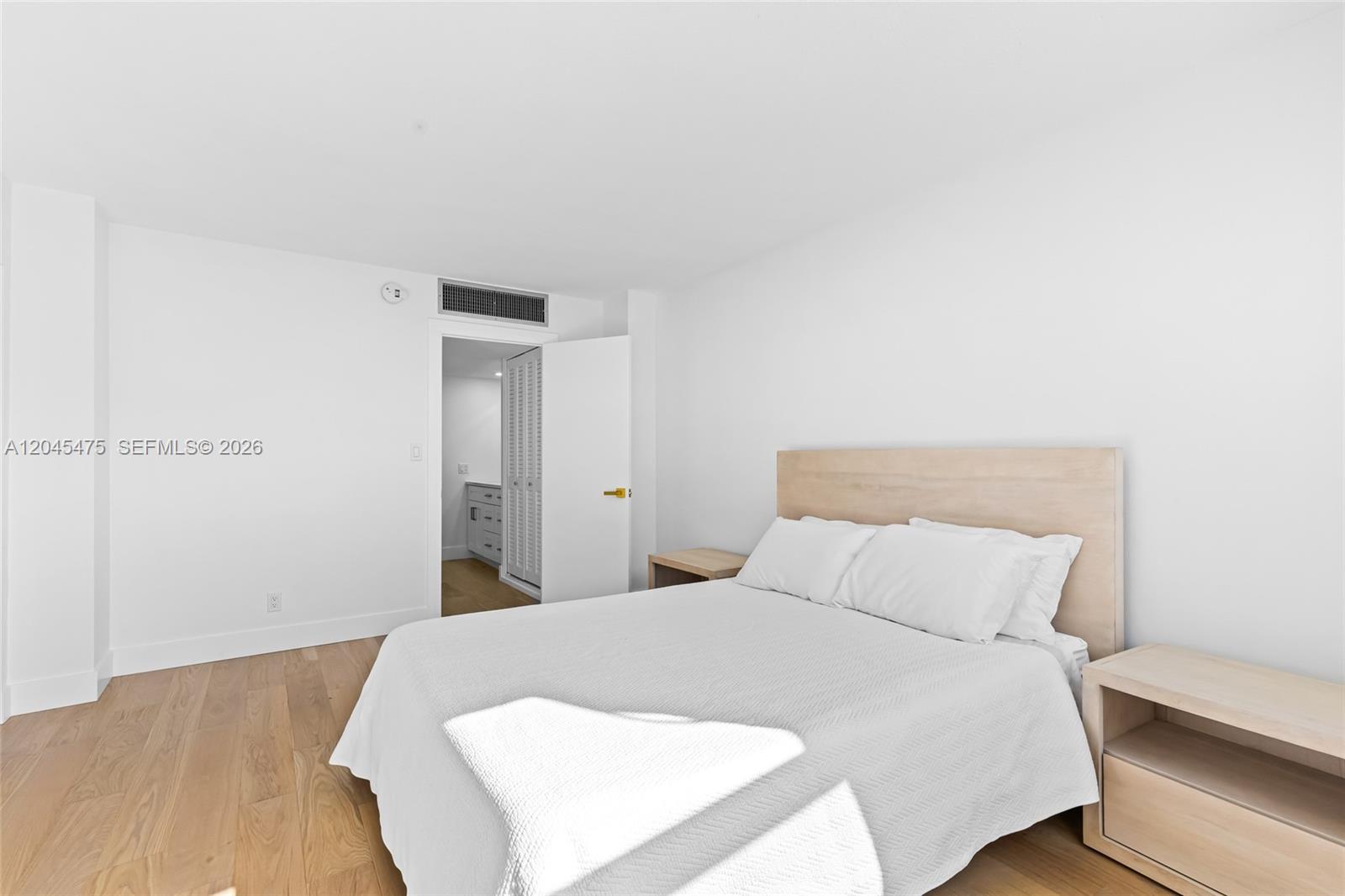 A bedroom features a light wood bed frame, white bedding, and light wood flooring — 301 N Ocean Blvd # 302, Pompano Beach FL 33062, POMPANO BEACH, FL