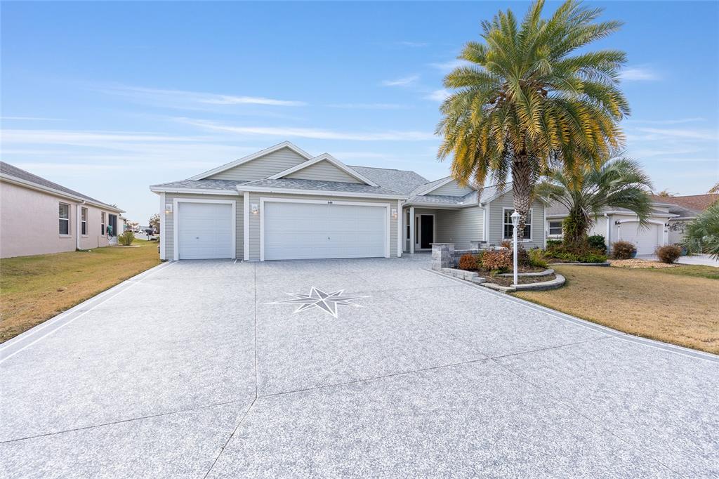 A single-story house with a three-car garage and a decorative star on the driveway — 840 FOLSUM PLACE, THE VILLAGES, FL