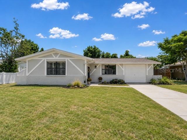 A single-story house with a light gray exterior, white trim, and a concrete driveway — 9414 LEDGESTONE LANE, PORT RICHEY, FL