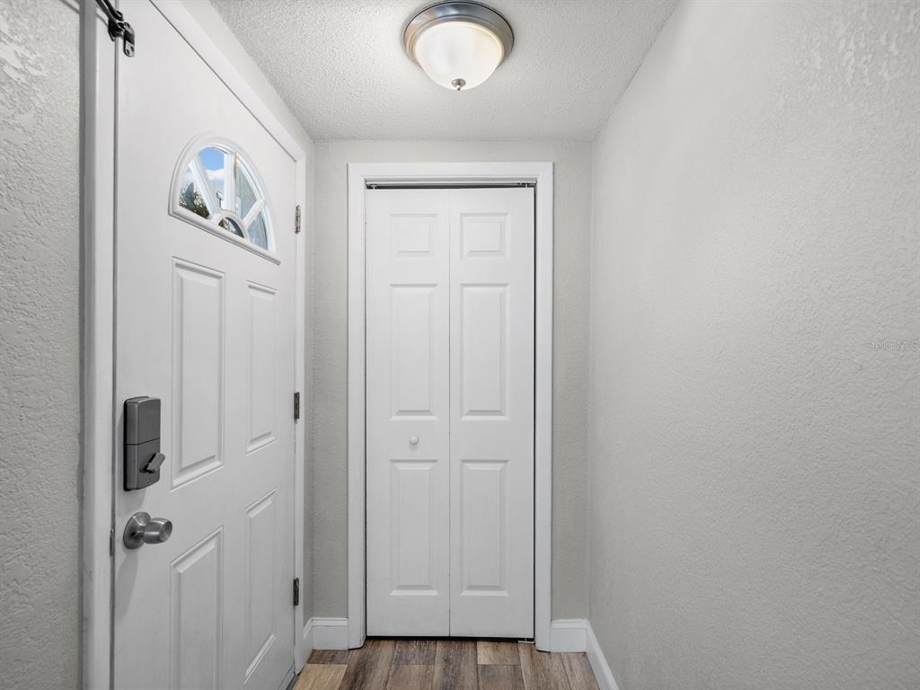 An entryway features a white front door, a bifold closet door, and a ceiling light — 9414 LEDGESTONE LANE, PORT RICHEY, FL