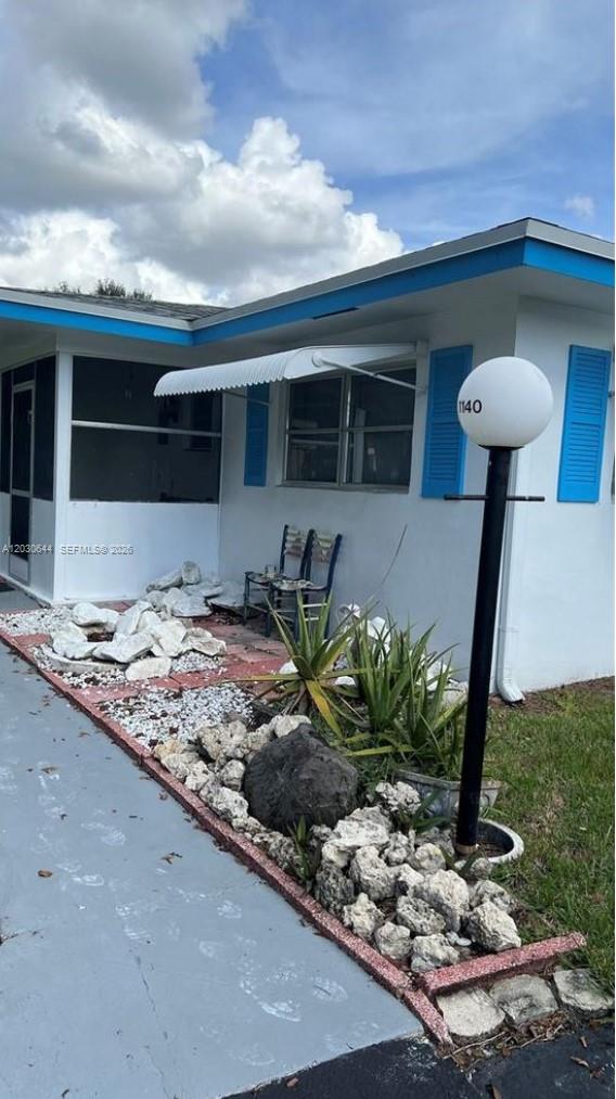 A white house exterior features a blue-trimmed roof, a small porch, and rock landscaping — 1140 NW 85th Ave, Plantation FL 33322, PLANTATION, FL