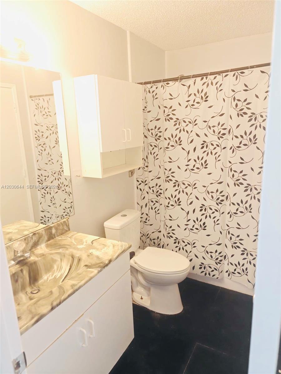 A bathroom features a vanity with a marble-patterned countertop, a toilet, and a shower curtain — 1140 NW 85th Ave, Plantation FL 33322, PLANTATION, FL
