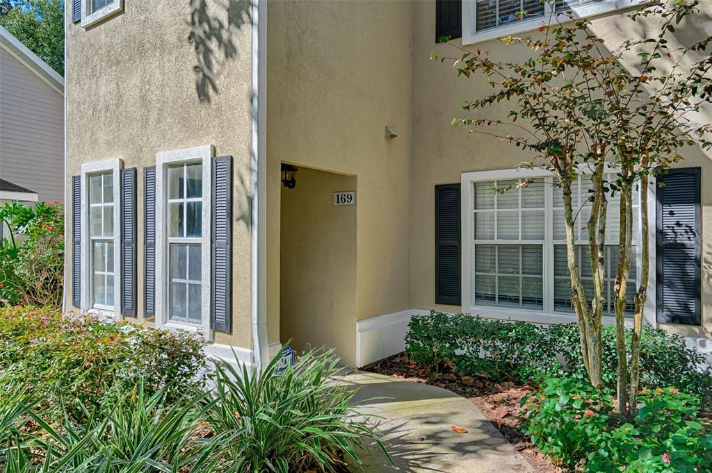 A covered balcony features a dining table with chairs overlooking a wooded area and golf course — 10000 SW 52ND AVENUE UNIT 169, GAINESVILLE, FL
