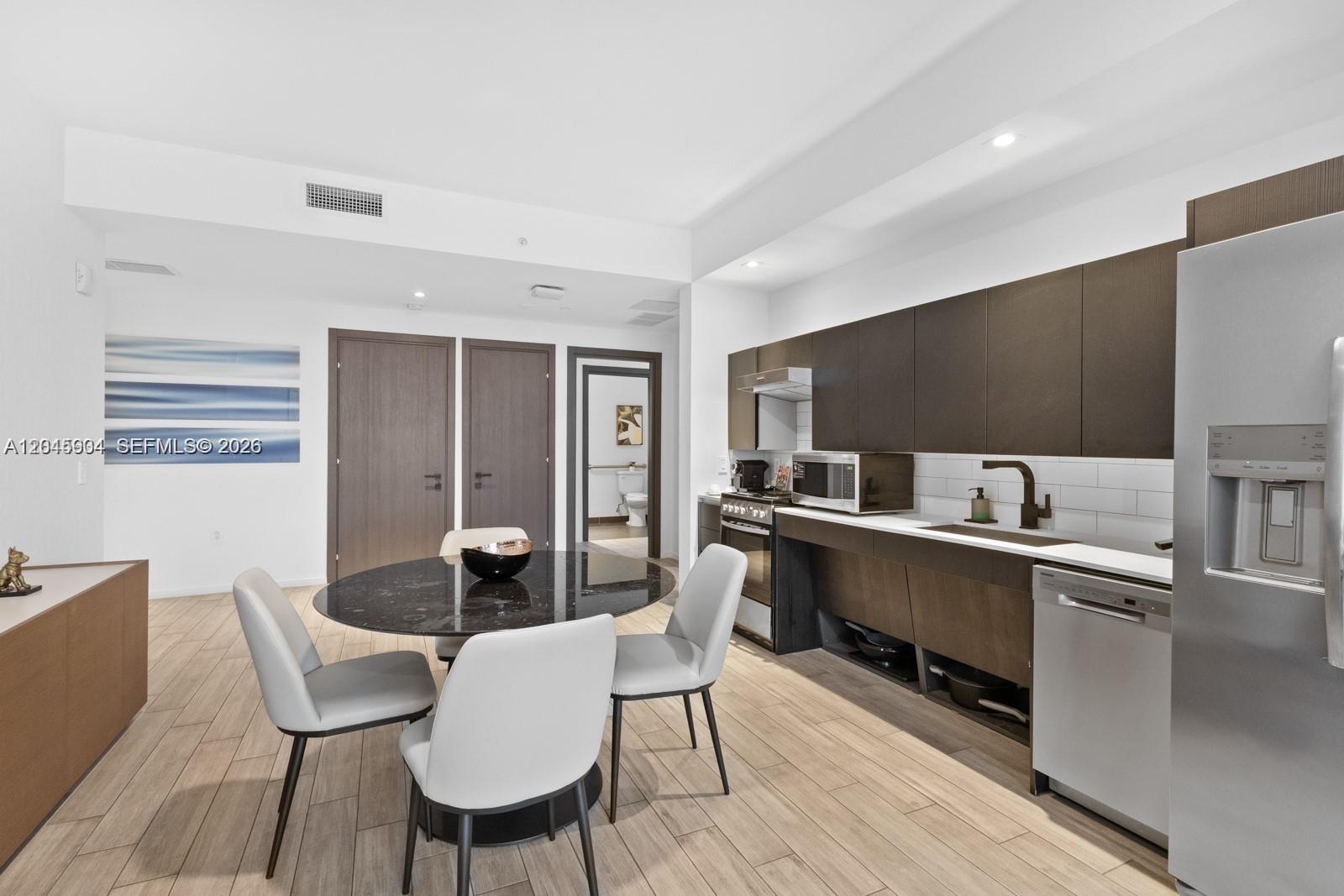 A modern kitchen features dark wood cabinetry, stainless steel appliances, and a round dining table — 398 NE 5th St # 1518, Miami FL 33132, MIAMI, FL