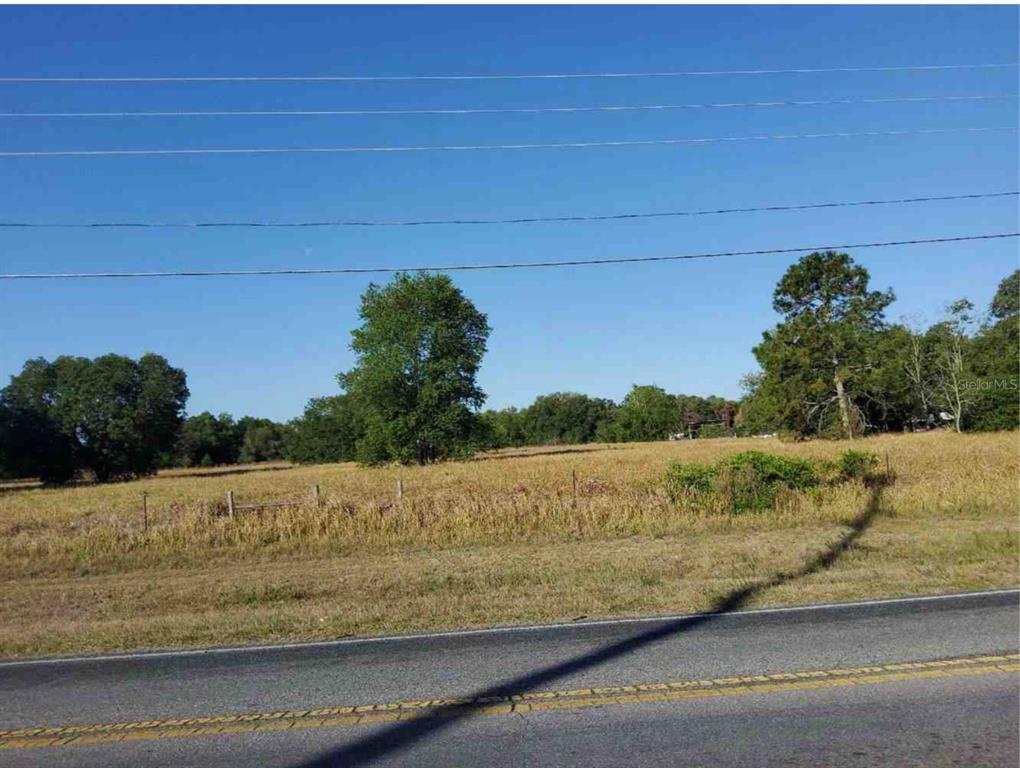 A view of a flat, grassy vacant lot bordering a paved road under a clear sky — MARICAMP ROAD, OCKLAWAHA, FL