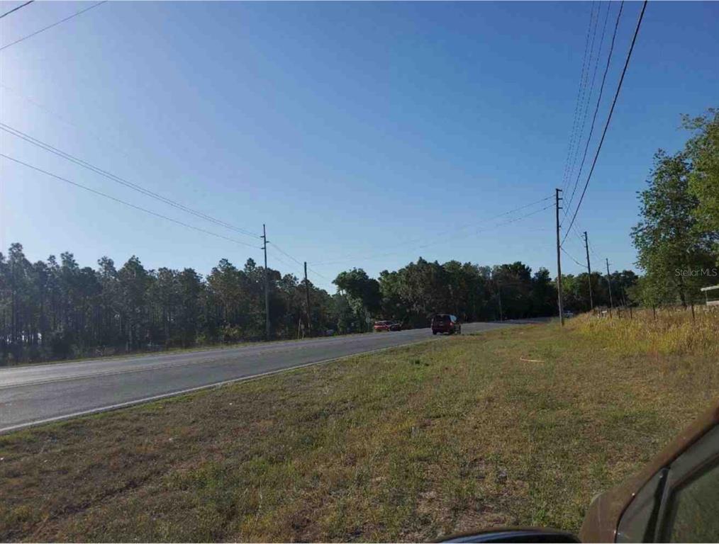 A paved road stretches past a grassy roadside area with trees and utility poles — MARICAMP ROAD, OCKLAWAHA, FL