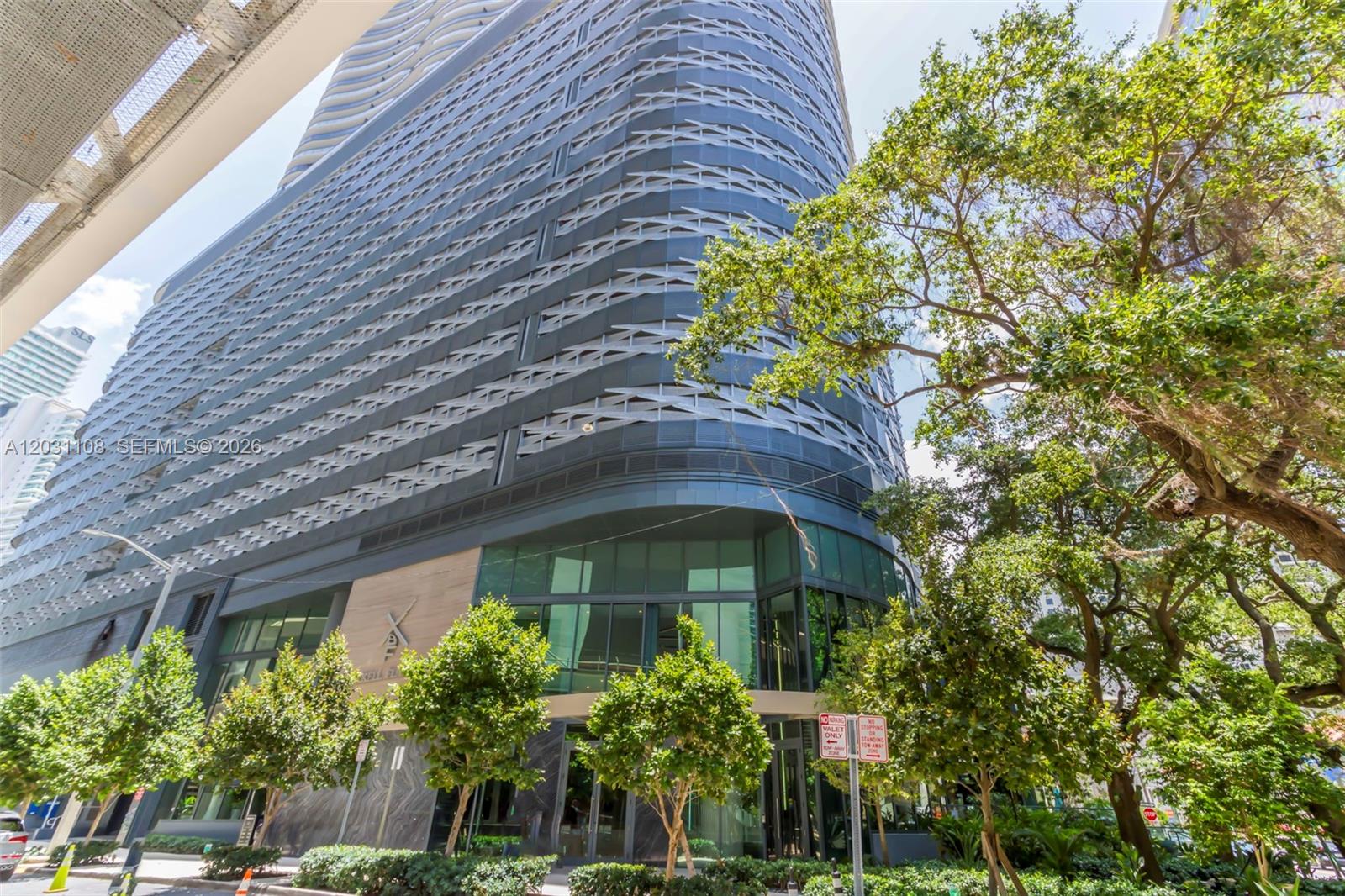 A modern high-rise building features a textured facade and a glass-enclosed ground-level entrance — 1000 Brickell Plz # 4609, Miami FL 33131, MIAMI, FL