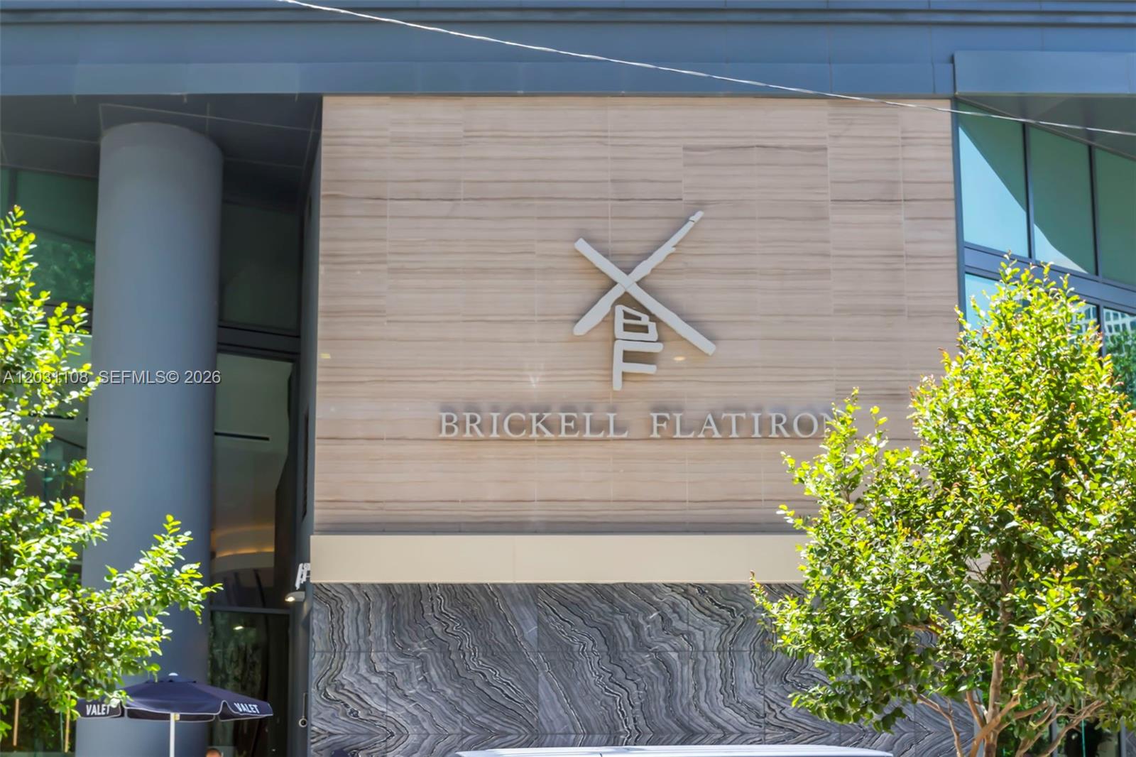 The exterior of the Brickell Flatiron building features a stone facade with a prominent logo — 1000 Brickell Plz # 4609, Miami FL 33131, MIAMI, FL