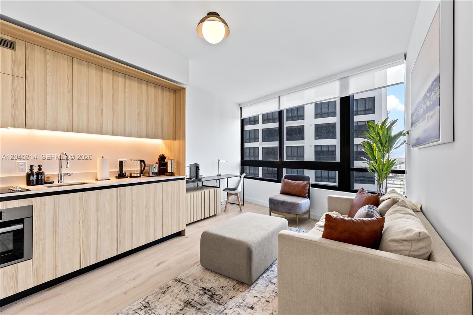 A modern studio apartment features light wood cabinetry, a kitchenette, and a living area — 225 N Miami Ave # 1102, Miami FL 33128, MIAMI, FL