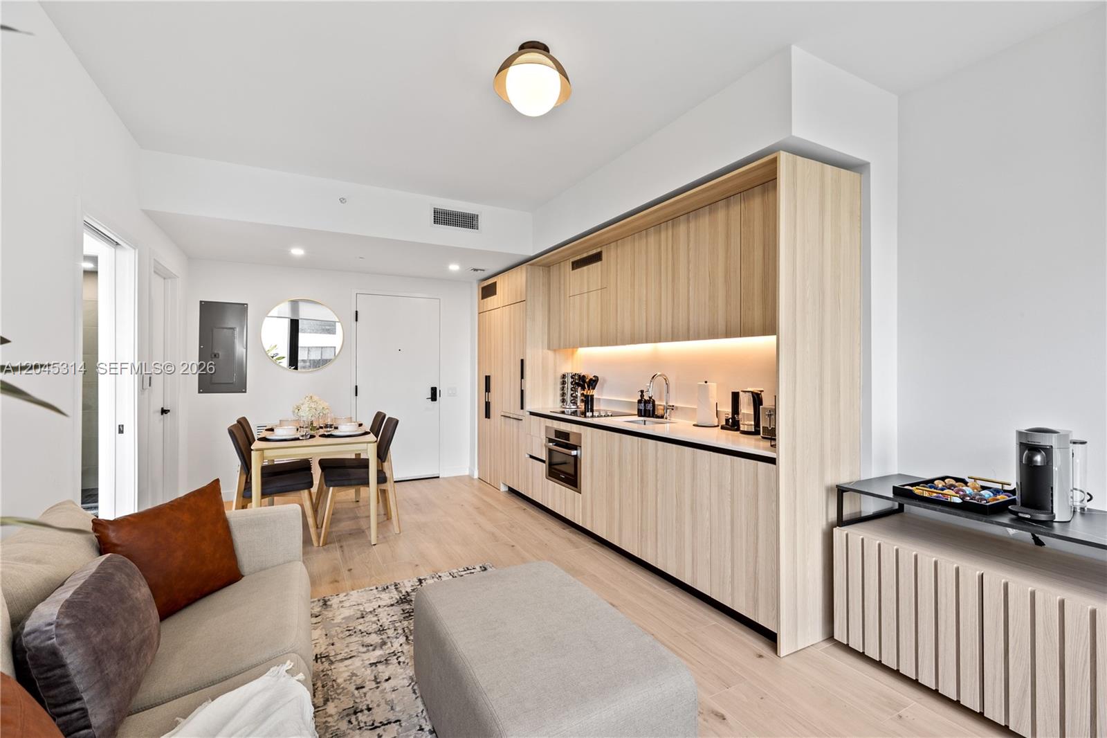 A modern studio apartment features a light wood kitchen, dining area, and living space — 225 N Miami Ave # 1102, Miami FL 33128, MIAMI, FL