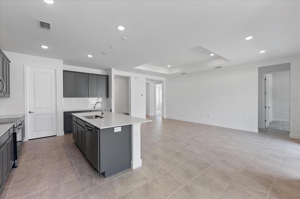 A kitchen with a gray island and cabinets, white countertops, and light tile flooring — 9593 VIBRANT LANE, VENICE, FL