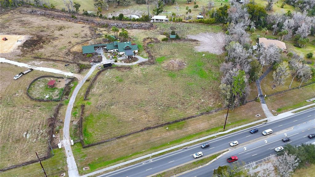 An aerial view shows a house with a green roof, a long driveway, and surrounding land — 1195 SW 42ND STREET, OCALA, FL