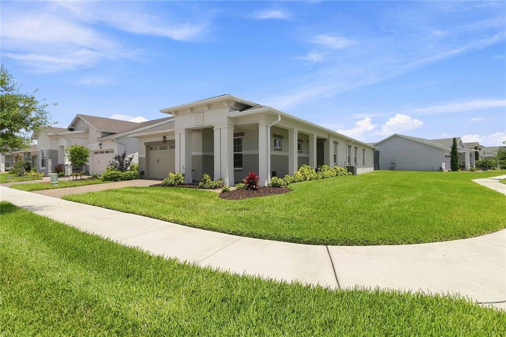 A single-story house with a beige exterior, a two-car garage, and a covered front porch — 2699 MIDSWEET AVENUE, ST CLOUD, FL